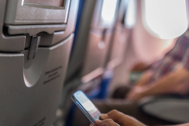 Bir adam bir ticari uçağın içinde cep telefonu kullanır - Fotoğraf, Görsel