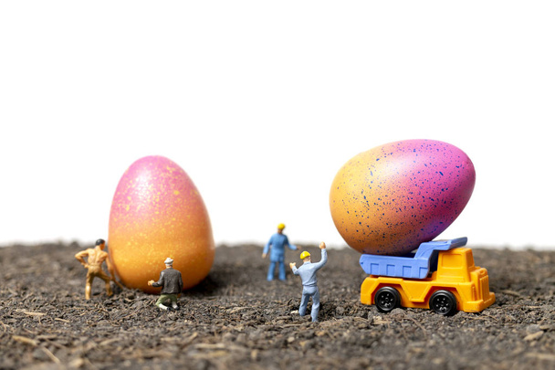 Personas en miniatura trabajan en huevos de Pascua para el día de Pascua con fondo blanco
 - Foto, Imagen