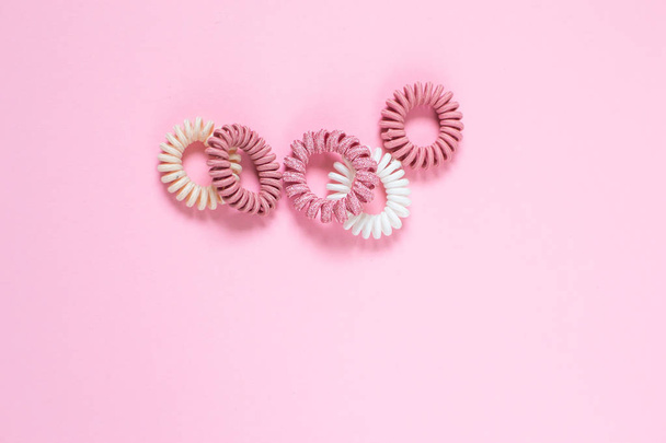 Спиральные резинки для волос на розовом фоне, концепция красоты, плоский уголок
 - Фото, изображение