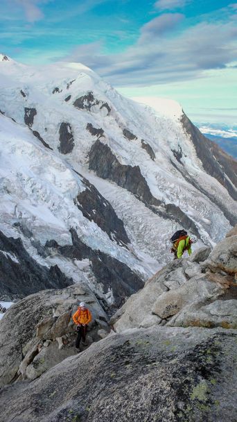 guide de montagne et client masculin sur une crête rocheuse et enneigée se dirigeant vers un sommet élevé dans les Alpes françaises près de Chamonix
 - Photo, image