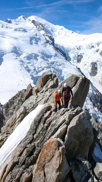 Bergführer und ein männlicher Kunde auf einem Fels- und Schneekamm auf dem Weg zu einem hohen Gipfel in den französischen Alpen bei Chamonix - Foto, Bild