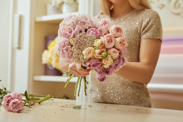 partial view of florist making bouquet of roses and peonies at workplace - Foto, Imagem