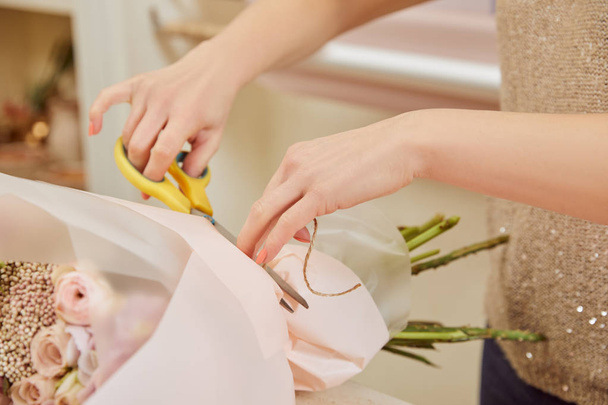 partial view of florist cutting strip with scissors on bouquet  - Photo, Image