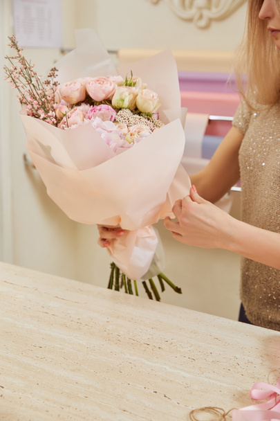 partial view of florist holding bouquet of roses and peonies at workspace - Photo, Image