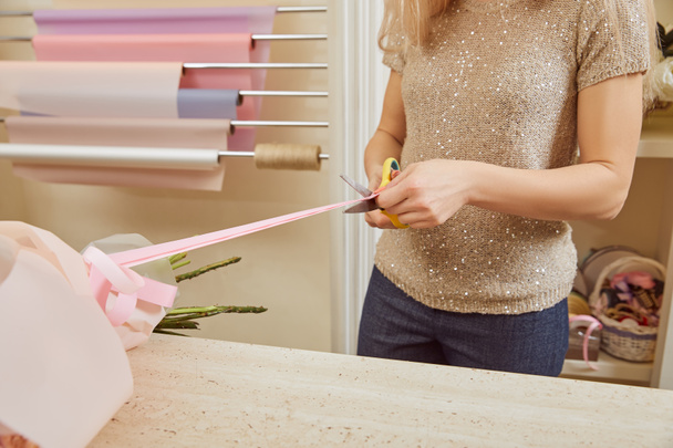 partial view of florist cutting strip with scissors on bouquet  - 写真・画像
