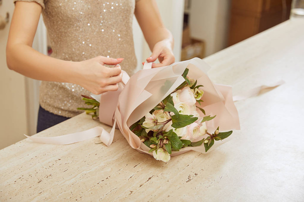partial view of florist tying ribbon bouquet of white peonies  - Foto, imagen