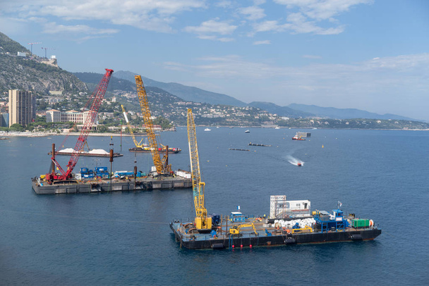 Um guindaste de construção barcaças começa trabalhos de recuperação de terras ao largo da costa de Mônaco
 - Foto, Imagem