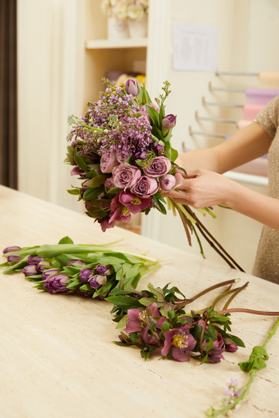 cropped view of florist making bouquet of tulips, peonies and lilac at workplace - Valokuva, kuva