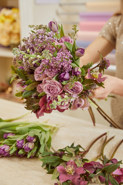 cropped view of woman making bouquet of tulips, peonies and lilac at workplace - Foto, immagini