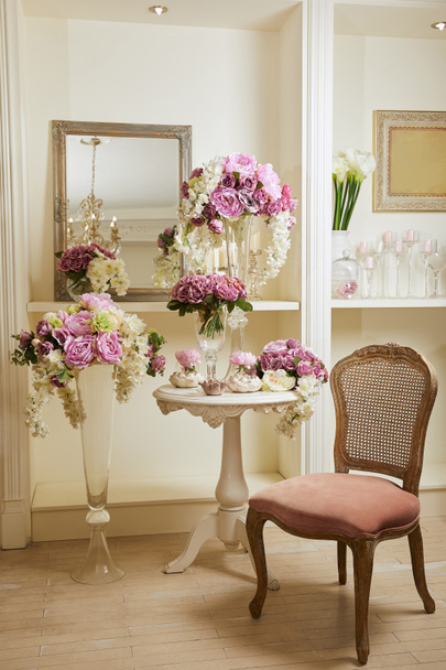 Intérieur de la chambre avec chaise, miroir, bouquets dans des vases en verre
 - Photo, image