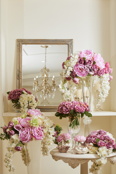 зеркало, белые и фиолетовые цветы в стеклянных вазах на столе и полке
  - Фото, изображение