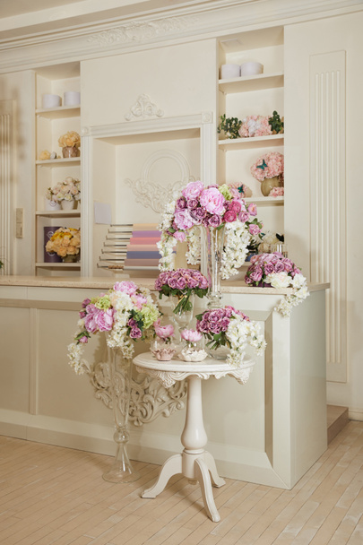 Interieur van kamer met rek, tafel en bloemen in glazen vazen - Foto, afbeelding