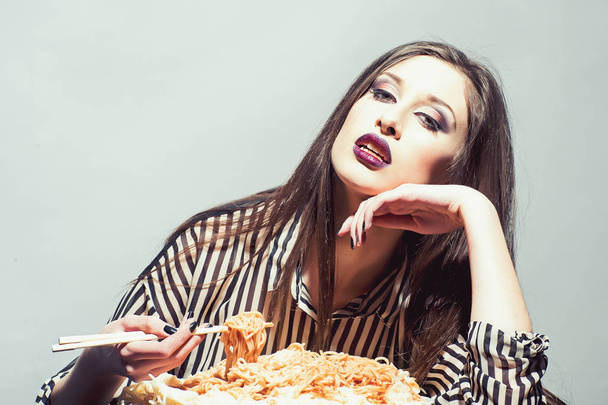 Hungry girl have italian food meal. Hungry woman eat spaghetti with chopsticks - Foto, imagen