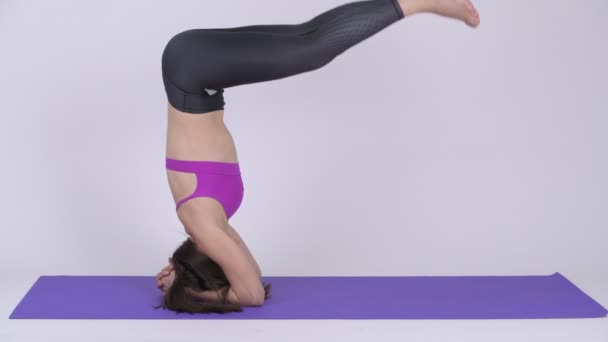 Young beautiful multi-ethnic woman doing Headstand yoga pose - Filmati, video