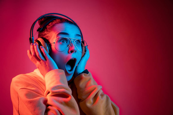 Fashion pretty woman with headphones listening to music over neon background - 写真・画像