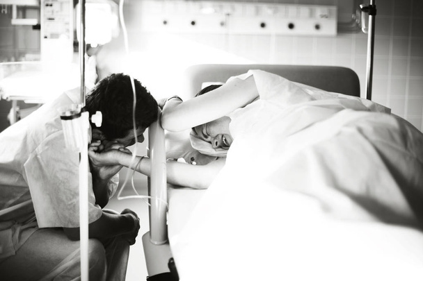Mąż trzyma w ręce jego ciężarna żona w szpitalu krótko przed narodzinami dziecka. - Zdjęcie, obraz