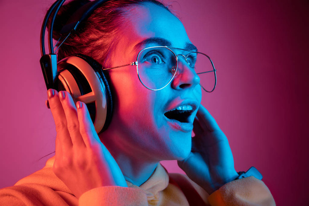 Fashion pretty woman with headphones listening to music over neon background - Photo, image