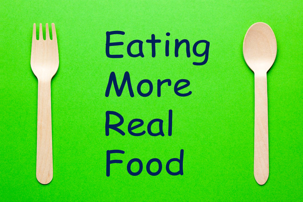 Essen mehr echte Lebensmittel Text mit Löffel und Gabel auf grünem Hintergrund. eat-Konzept. - Foto, Bild