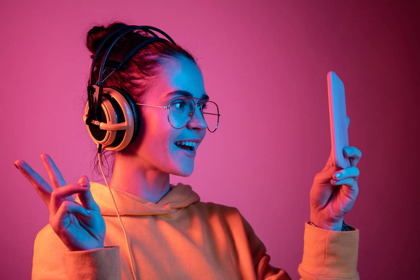 Moda bella donna con le cuffie ascoltare musica su sfondo neon
 - Foto, immagini