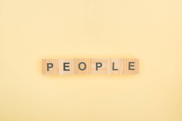 top view of people lettering made of wooden cubes on yellow background - Fotografie, Obrázek