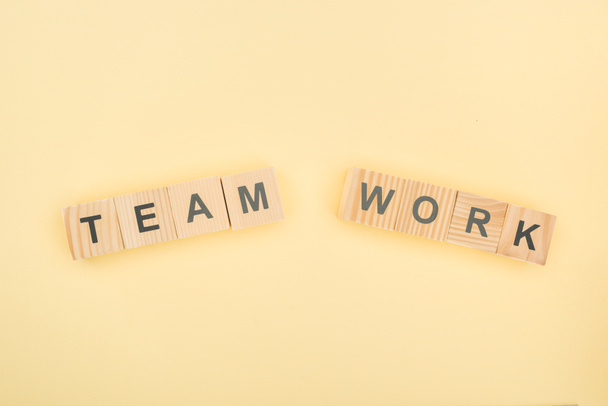 top view of team work lettering made of wooden cubes on yellow background - Φωτογραφία, εικόνα