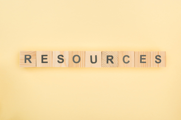 top view of resources lettering made of wooden cubes on yellow background - Foto, Bild