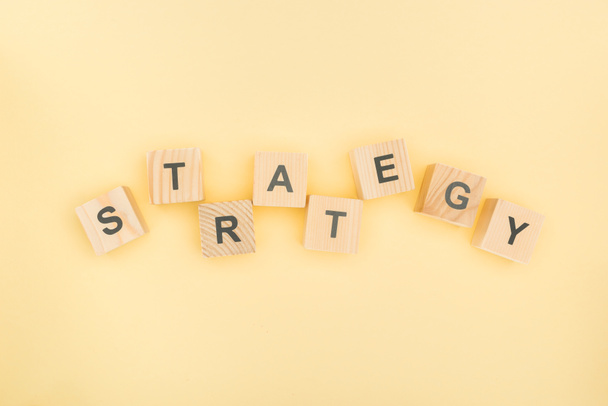 top view of strategy lettering made of wooden blocks on yellow background - Fotografie, Obrázek