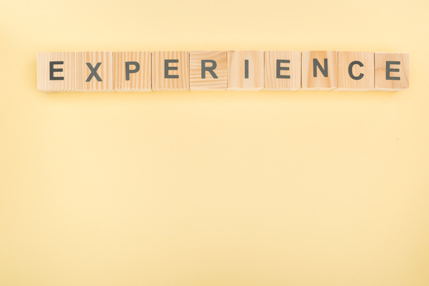 top view of experience lettering made of wooden blocks on yellow background - Foto, Imagen