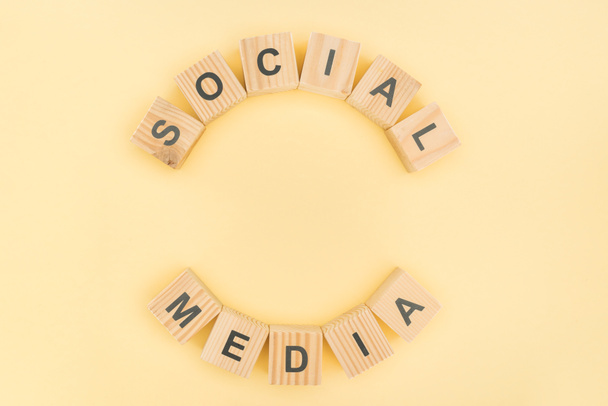 top view of social media phrase made of wooden blocks on yellow background - Foto, afbeelding