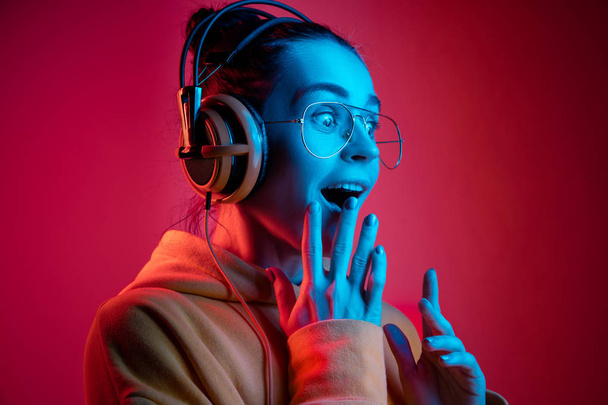 Fashion pretty woman with headphones listening to music over neon background - Foto, Imagem