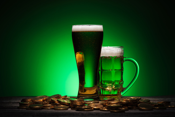 glasses of beer standing on wooden table on st patricks day on green background - Foto, Imagen