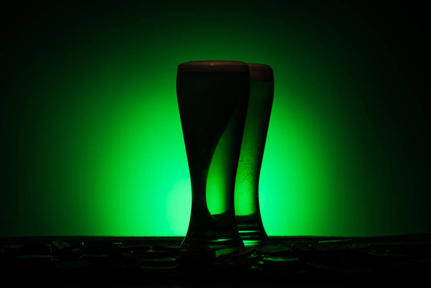 silhouette of glasses of irish beer standing on table on green background - Photo, Image