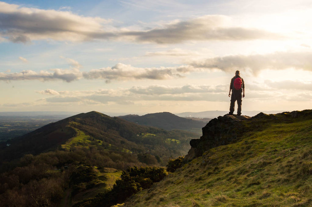 A lone hiker looking out across the ridge of the Malvern Hills on a sunny winters afternoon. Malvern Hills, England. - Photo, image