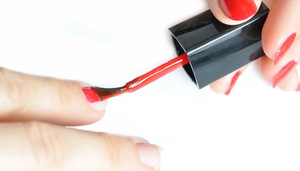 Young girl painting her nails red - 写真・画像