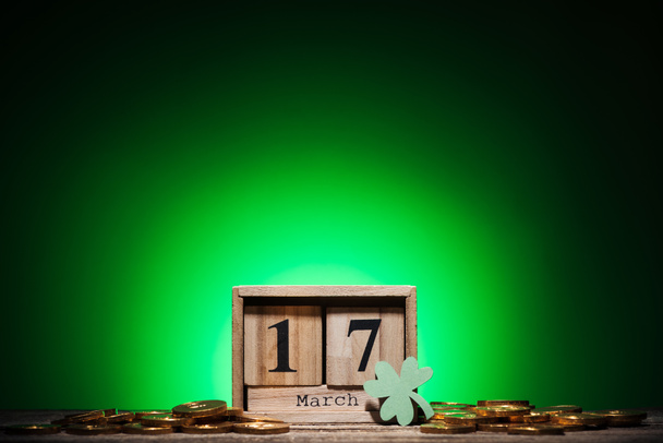 calendário cubo com data perto de moedas de ouro e trevo em fundo verde
 - Foto, Imagem