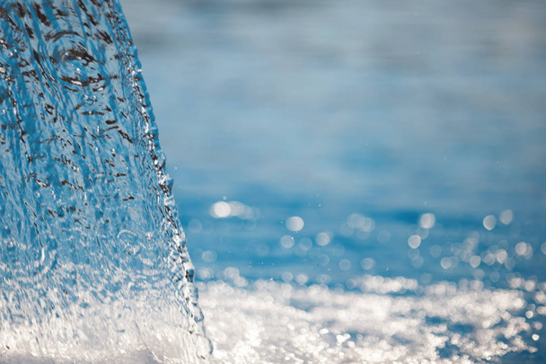 Ρεύμα του νερού στην πισίνα. Μπλε επιφάνεια, σπρέι, γκρο πλαν. Επιλεγμένο εστίαση. - Φωτογραφία, εικόνα