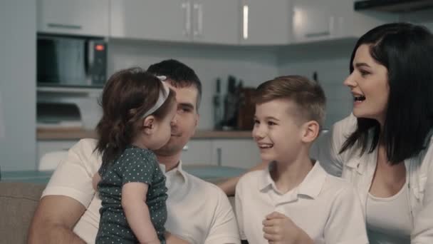 Ευτυχισμένη οικογένεια κάθεται στον καναπέ στο σπίτι - Πλάνα, βίντεο