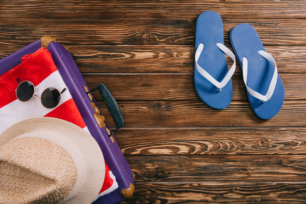 vue de dessus des accessoires d'été et des tongs près de la valise sur fond en bois
 - Photo, image