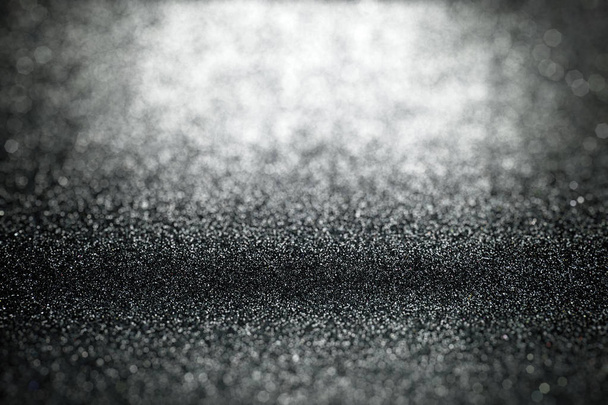 Glitter pozadí s selektivní fokus na povrchových textur s rozmazané popředí a pozadí abstraktní černé světlo - Fotografie, Obrázek