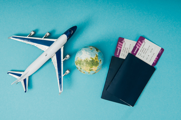 vista superior de los modelos de globo y avión, pasaportes con billetes sobre fondo azul
 - Foto, Imagen