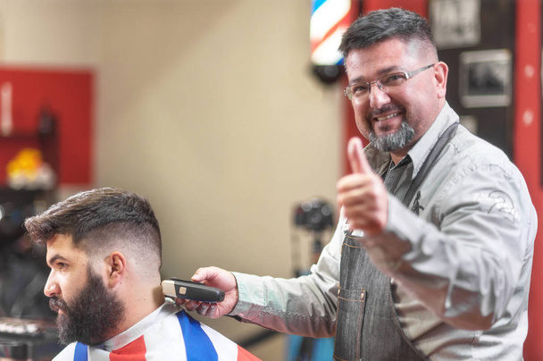 Ritratto di un barbiere che lavora mostrando il pollice in alto. Segno di approvazione positivo
. - Foto, immagini