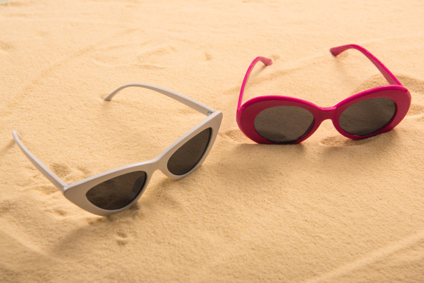 pink and white sunglasses on golden clear sand - Foto, imagen