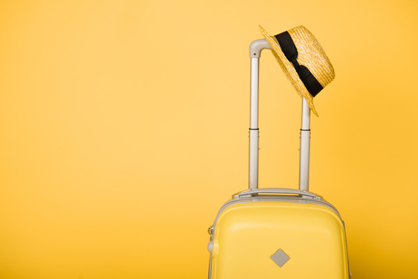 bright yellow travel bag and straw hat on yellow background - Photo, Image