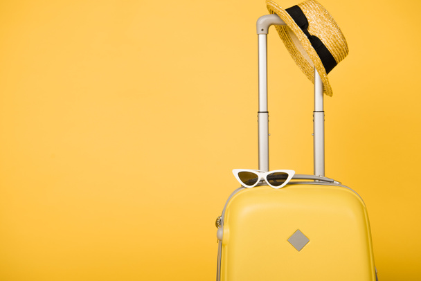 bright yellow travel bag, sunglasses and straw hat on yellow background - Φωτογραφία, εικόνα