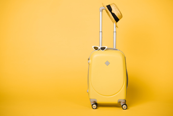 valise jaune vif, lunettes de soleil et chapeau de paille sur fond jaune
 - Photo, image