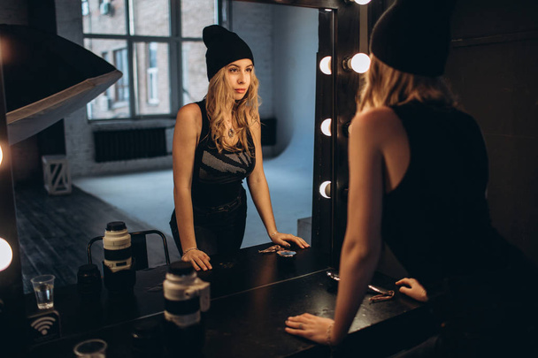 Portrait of a beautiful fashionable woman, blonde, jeans, posing in front of a mirror - Fotografie, Obrázek