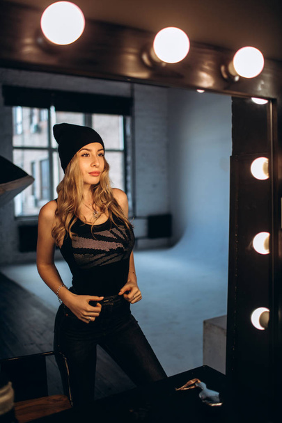 Portrait of a beautiful fashionable woman, blonde, jeans, posing in front of a mirror - Fotoğraf, Görsel