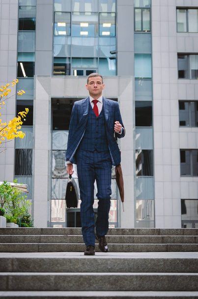 Vakava liikemies ruudullisessa tyylikkäässä puvussa tulossa alas portaita. Liikeelämä kaupungissa. Modernin liikemiehen muotokuva
 - Valokuva, kuva