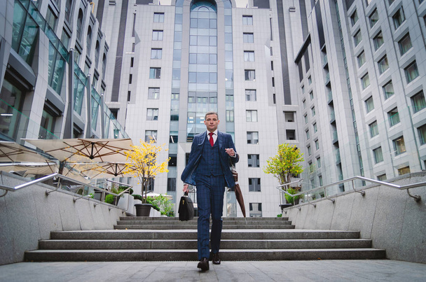 Homme d'affaires sérieux en costume élégant à carreaux descendant les escaliers. La vie des affaires en ville. Portrait d'un homme d'affaires moderne
 - Photo, image