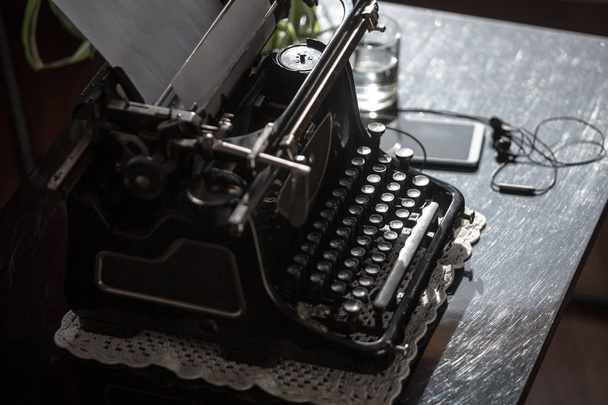 Workplace of an old school writer with mobile phone headphones and a typewriter - Fotó, kép